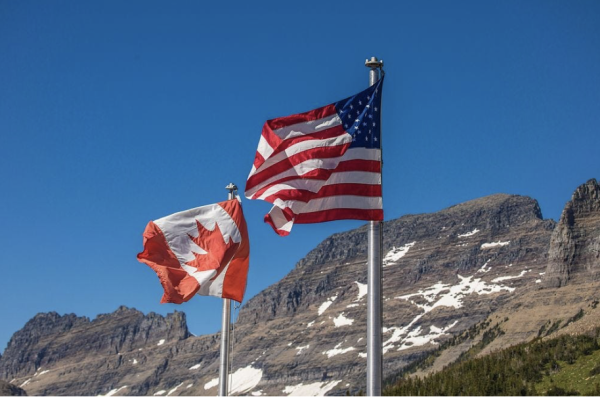 A flag of the United States and Canada planted on a mountain. | Via CreativeCommons